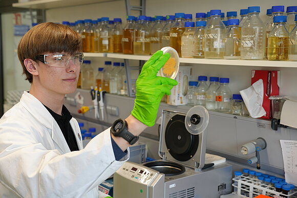 Alexander Becker in lab coat looking at petri dish