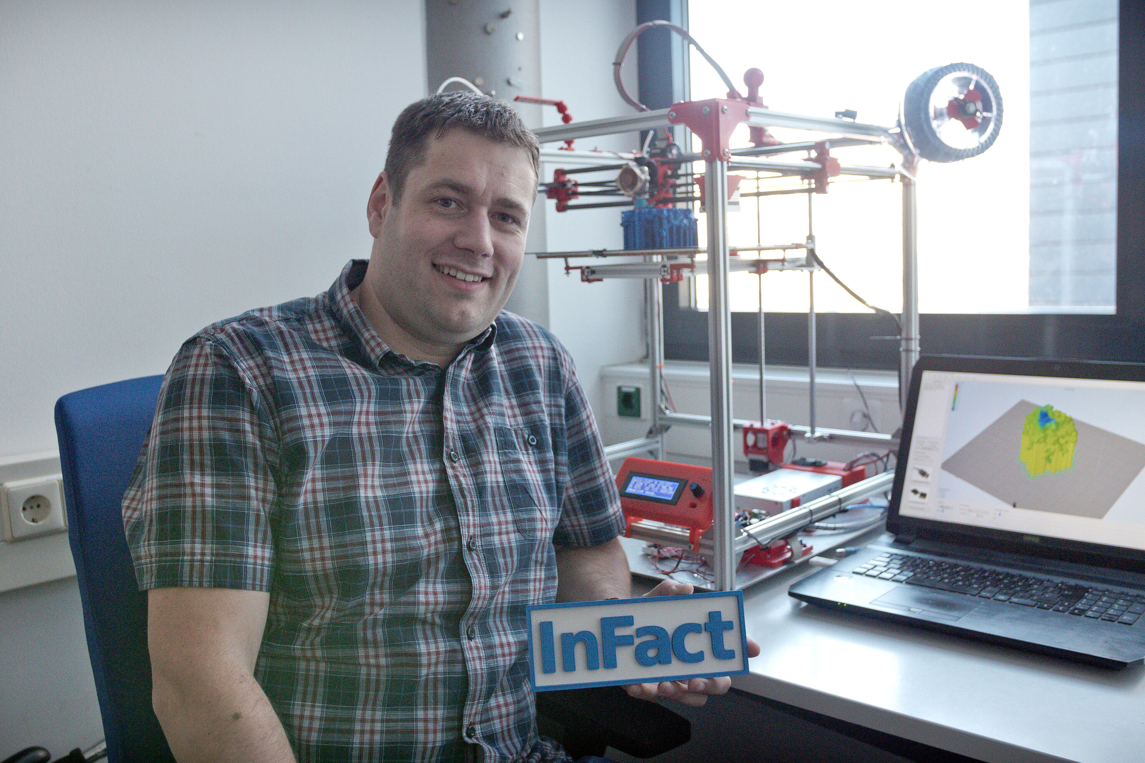 Stefan Schmelz at his desk with 3D printer and laptop