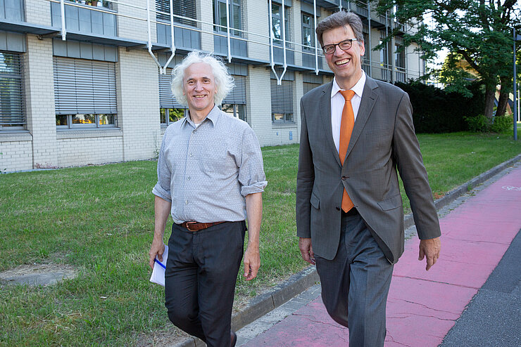 Josef Penninger und Christian Scherf laufen nebeneinander auf dem HZI Campus.