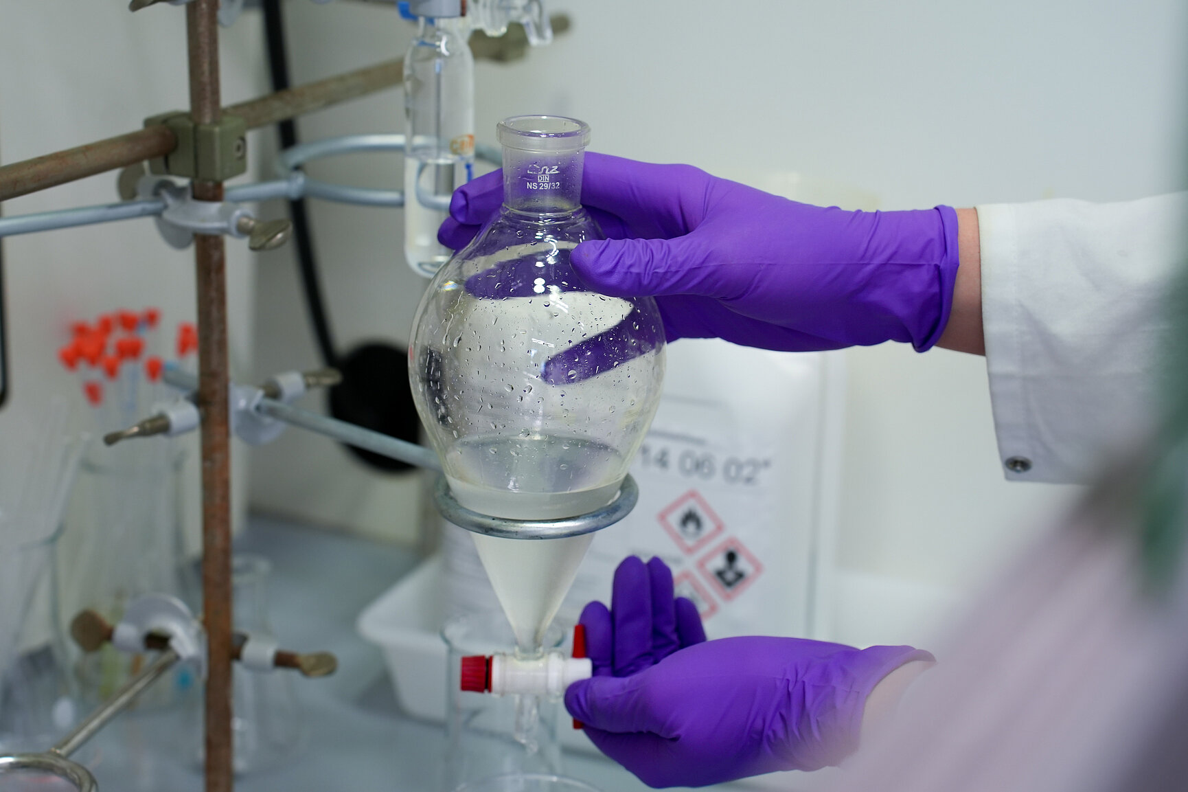 Person wearing purple gloves performing chemical synthesis