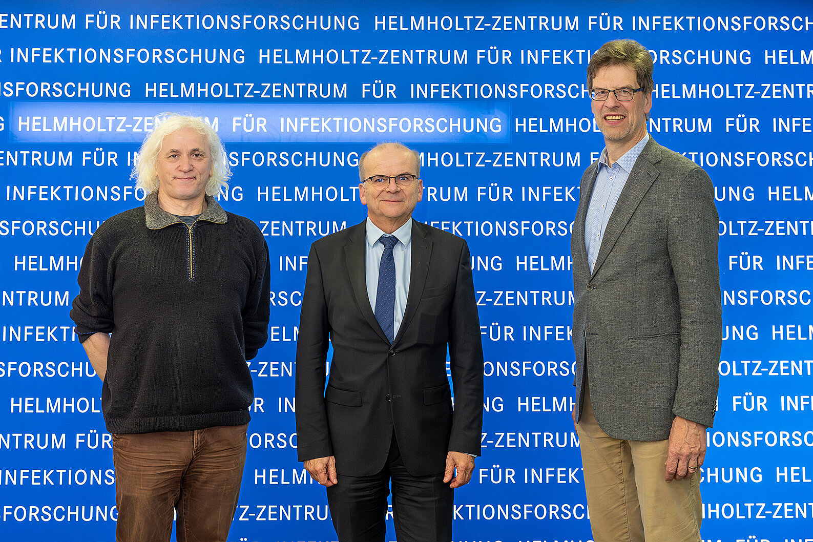 Three men against a blue background