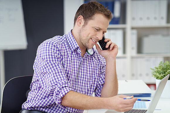 Man working on his laptop and talking on the phone