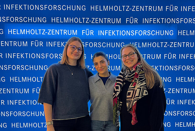 Group photo with 3 people in front of a blue banner