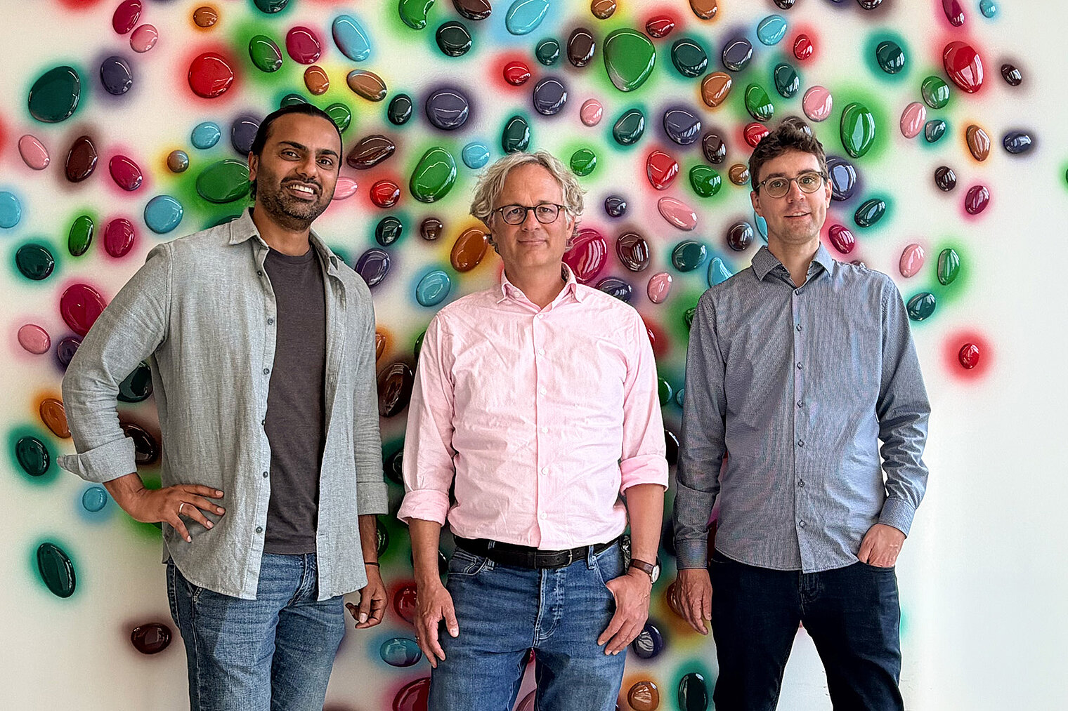 Group photo with three men in front of a wall with colorful dots