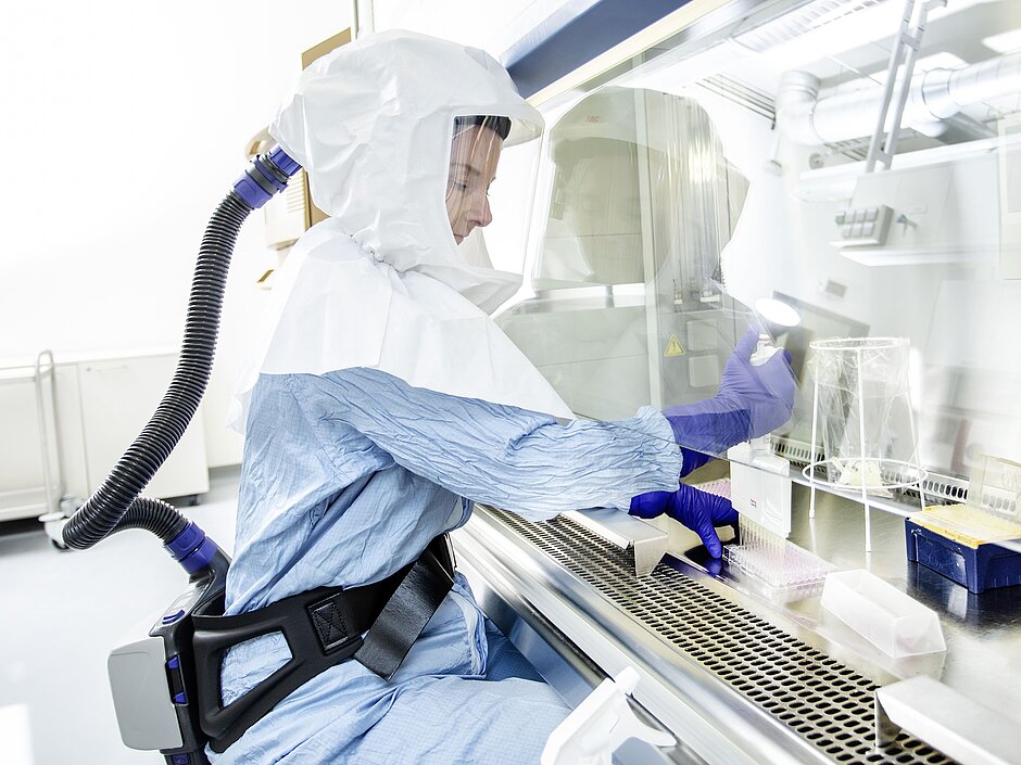 Scientist works in S3 protective suit at sterile workbench