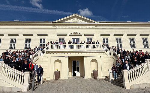 Gruppenfoto mit etwa 100 Personen auf Treppen vor einem Hauseingang