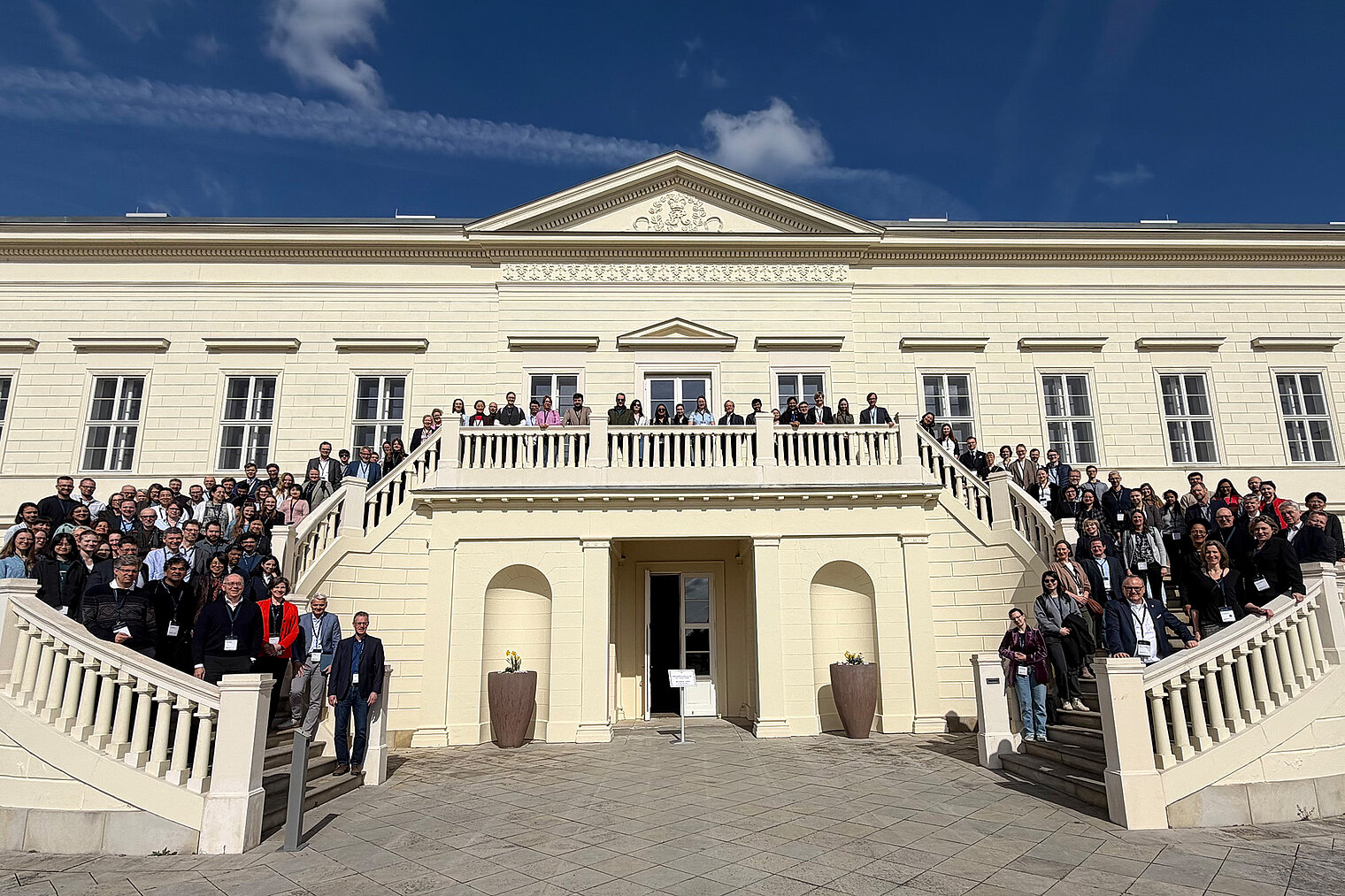 Group photo of about 100 people on the steps in front of a building entrance